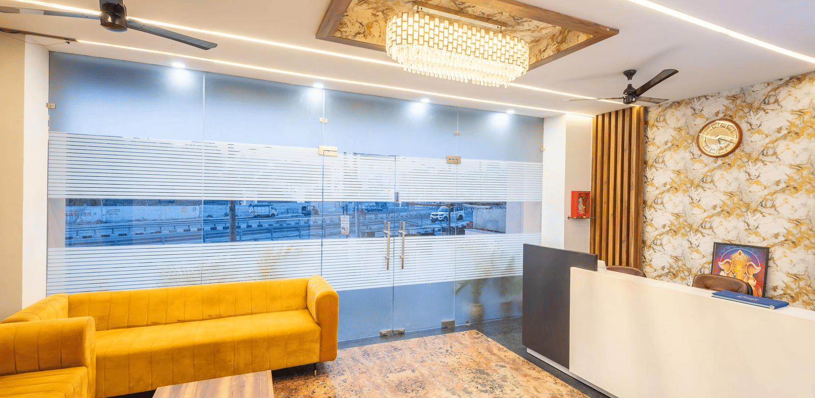 A hotel lobby showing a reception desk, a sofa seating area, and ceiling fan at Perfectstayz Premium Shanti Heritage, Haridwar