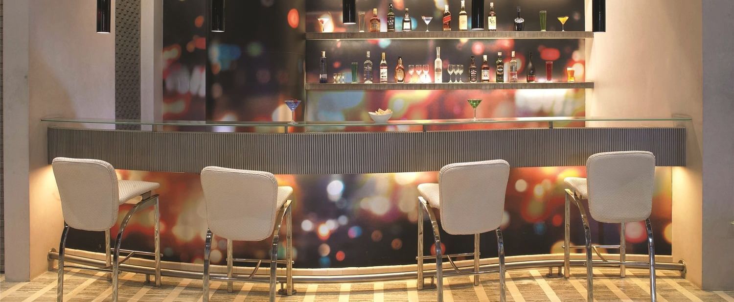 Image of zebra lounge at our hotel featuring a bar stand with chairs and bottles of alcohol | Mirage Hotel