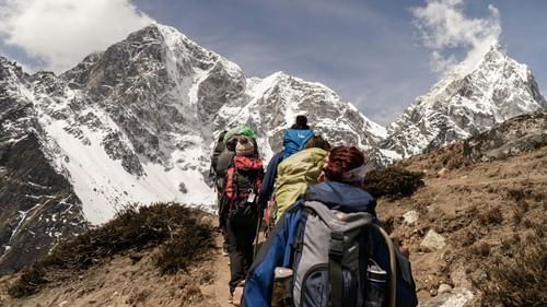 A group of people on a trek surrounded by snow capped mountains