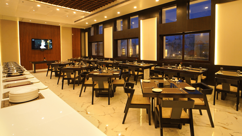A restaurant at Shanti Seaview Resort & Spa with neatly arranged dining tables, warm lighting, and large windows.