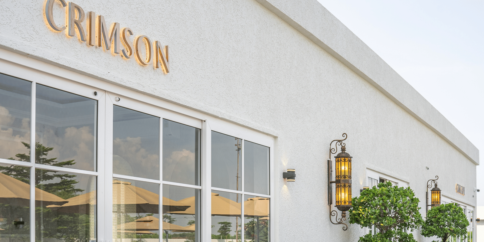 Exterior of a white building with large glass windows and the name Crimson in gold letters above the entrance at Hotel Hukam's Lalit Mahal.
