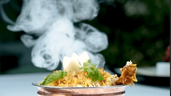 A steaming dish in a copper pot, with smoke rising and a blurred background at Cenneys Gateway.