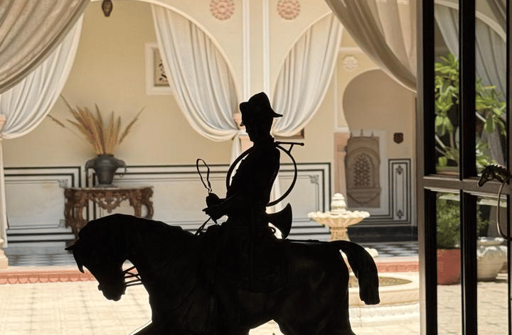 A silhouette of a person seated gracefully on horse statue surrounded by draped curtains - Khas Bagh, Jaipur.