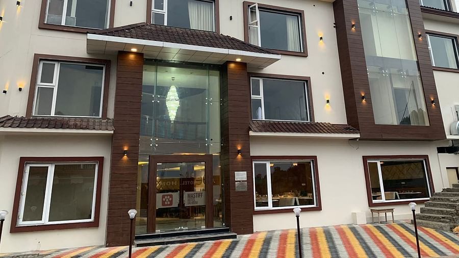 exterior of a hotel building that is shot from a lower angle during the day with a multicolour carpet on the floor near the entrance 