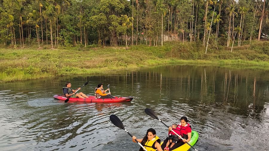 People in life jackets paddling kayaks on a serene river with dense forest in the background - Evergreen County