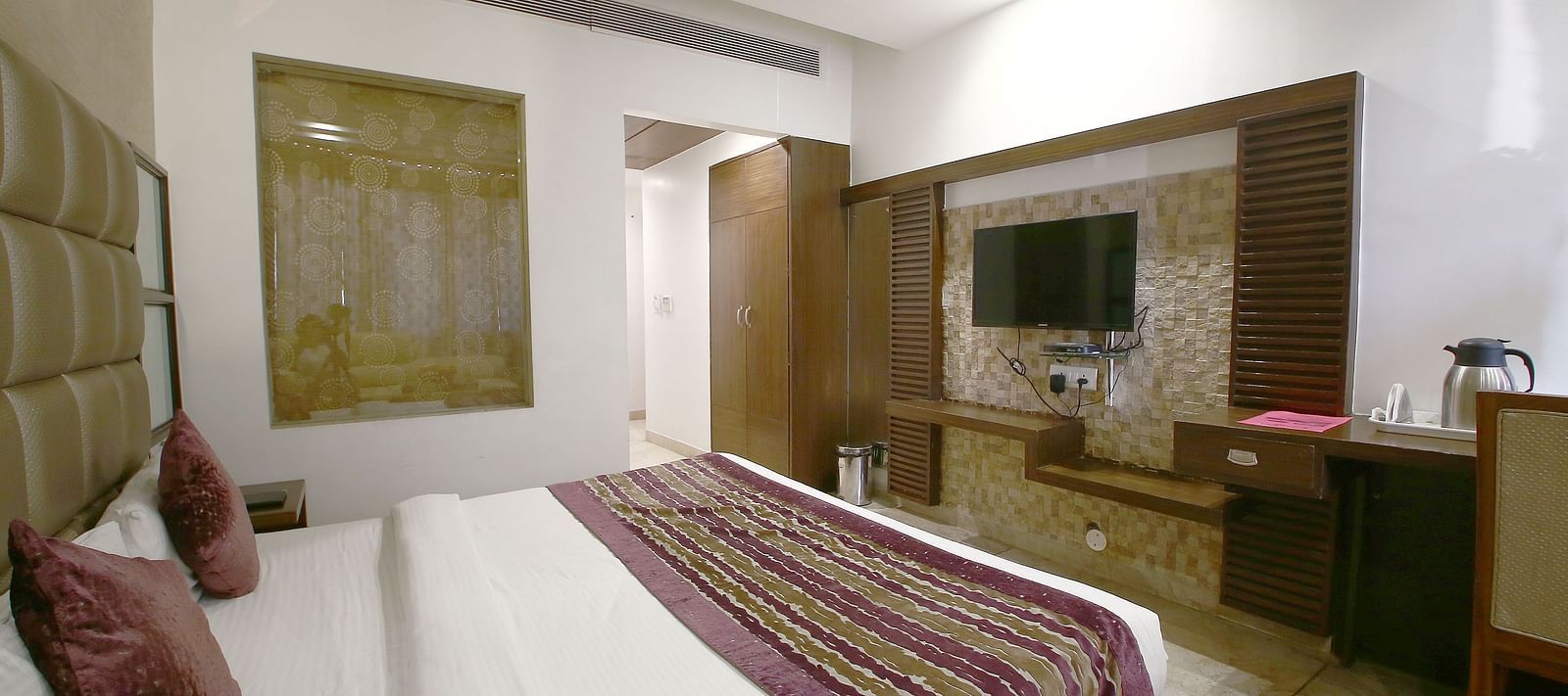 A spacious hotel room with a comfortable double bed, elegant decor, and a flat-screen television - Hotel Emerald, Chandigarh