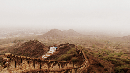 A wide shot of an ancient stone wall on a hill in a foggy landscape.