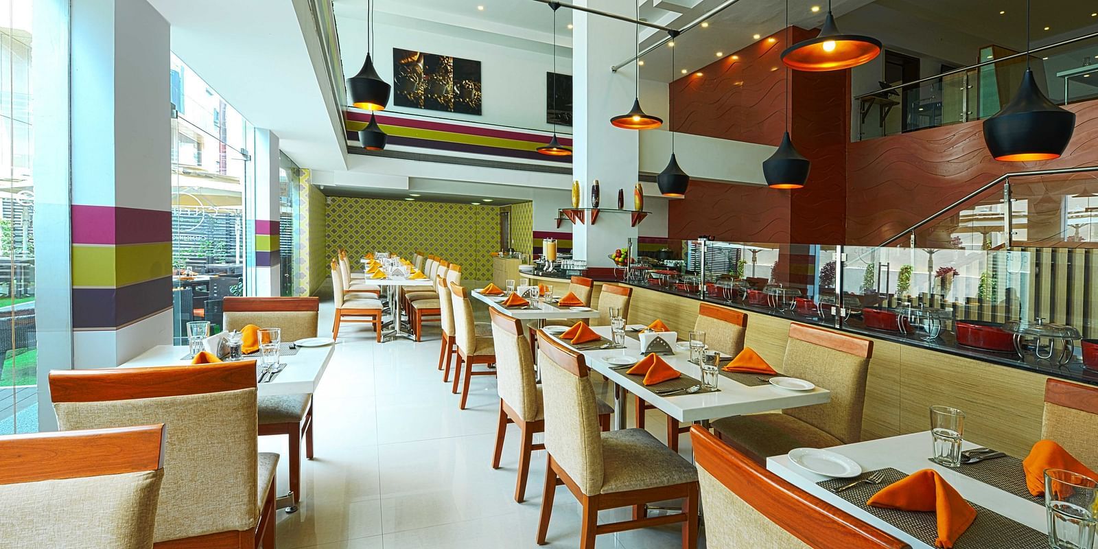 Coffee Shop at The Cunningham Hotel featuring modern decor, warm lighting, neatly arranged tables, and large windows overlooking the outdoors