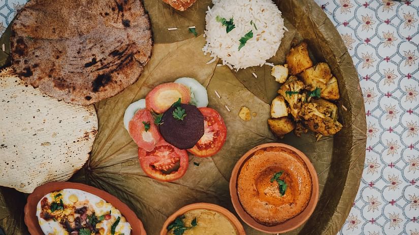 A traditional Indian thali being served on a plate made of dried leaves