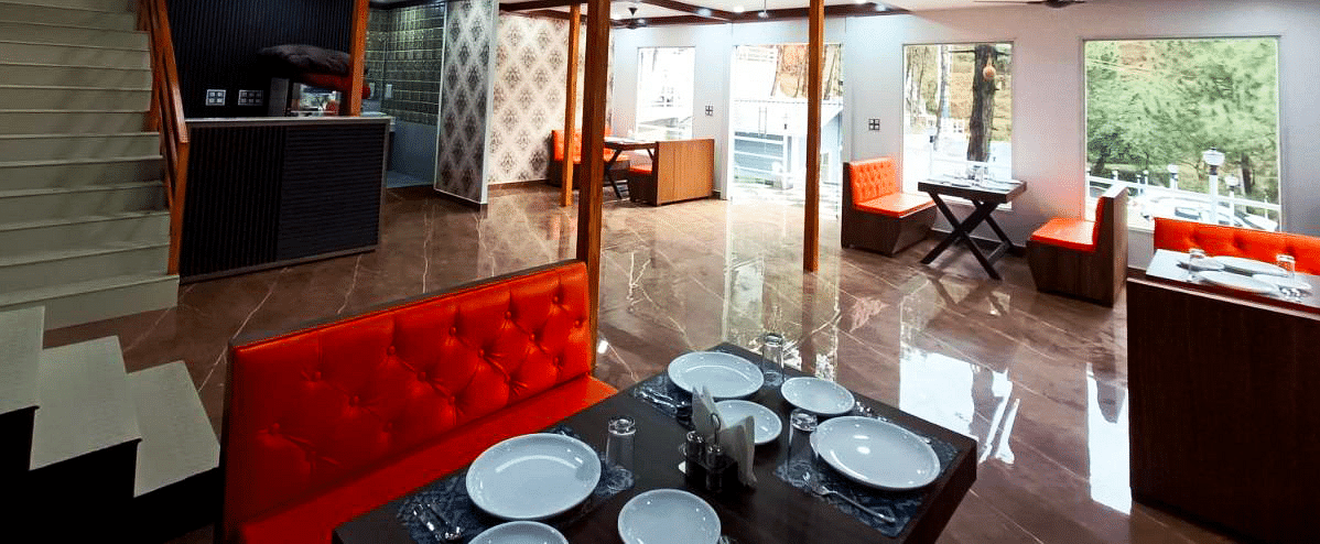 The interiors of the restaurant at DLS Nature Trinket Resort with red couches and tables.
