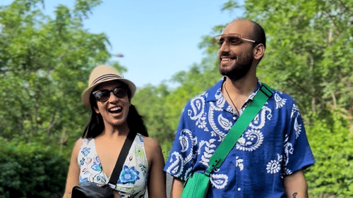 A couple walking on a tarred road with greenery in the background - Karma Lakelands.