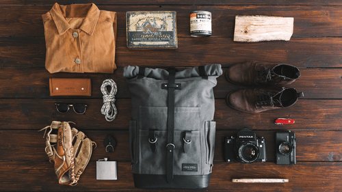 Dslr and jacket and other trip essentials on a wooden table