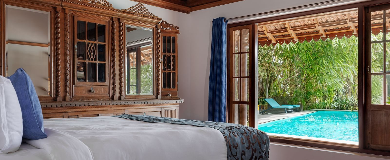 A shot of a room taken from an angle showcasing the bed facing a huge window with the view of the pool outside - BluSalzz Villas - Muhamma Resort, Alleppey