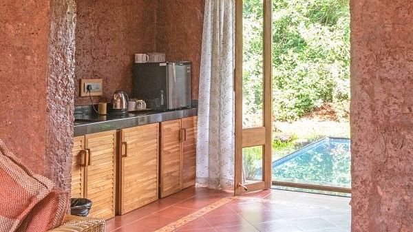 Rustic room with terracotta walls, wooden furnishings, and a view of a private pool through a sliding glass door.