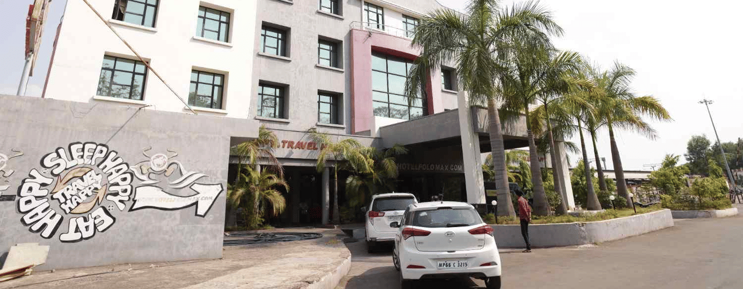  A facade image of max hotel situated on a street with palm trees.