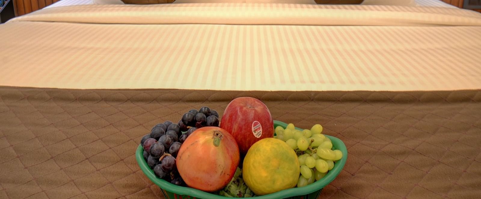 An image of a bed with a plate filled with a variety of fresh fruits placed on top at Hari Govindas, Siddappa Square.