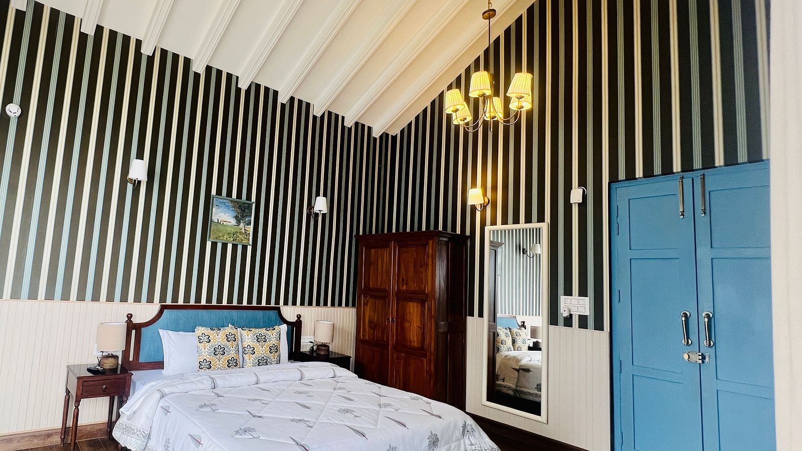 Luxurious hotel room with black and white striped wallpaper, a vintage wooden bed, and elegant blue doors | Faraway Cottages, Auli