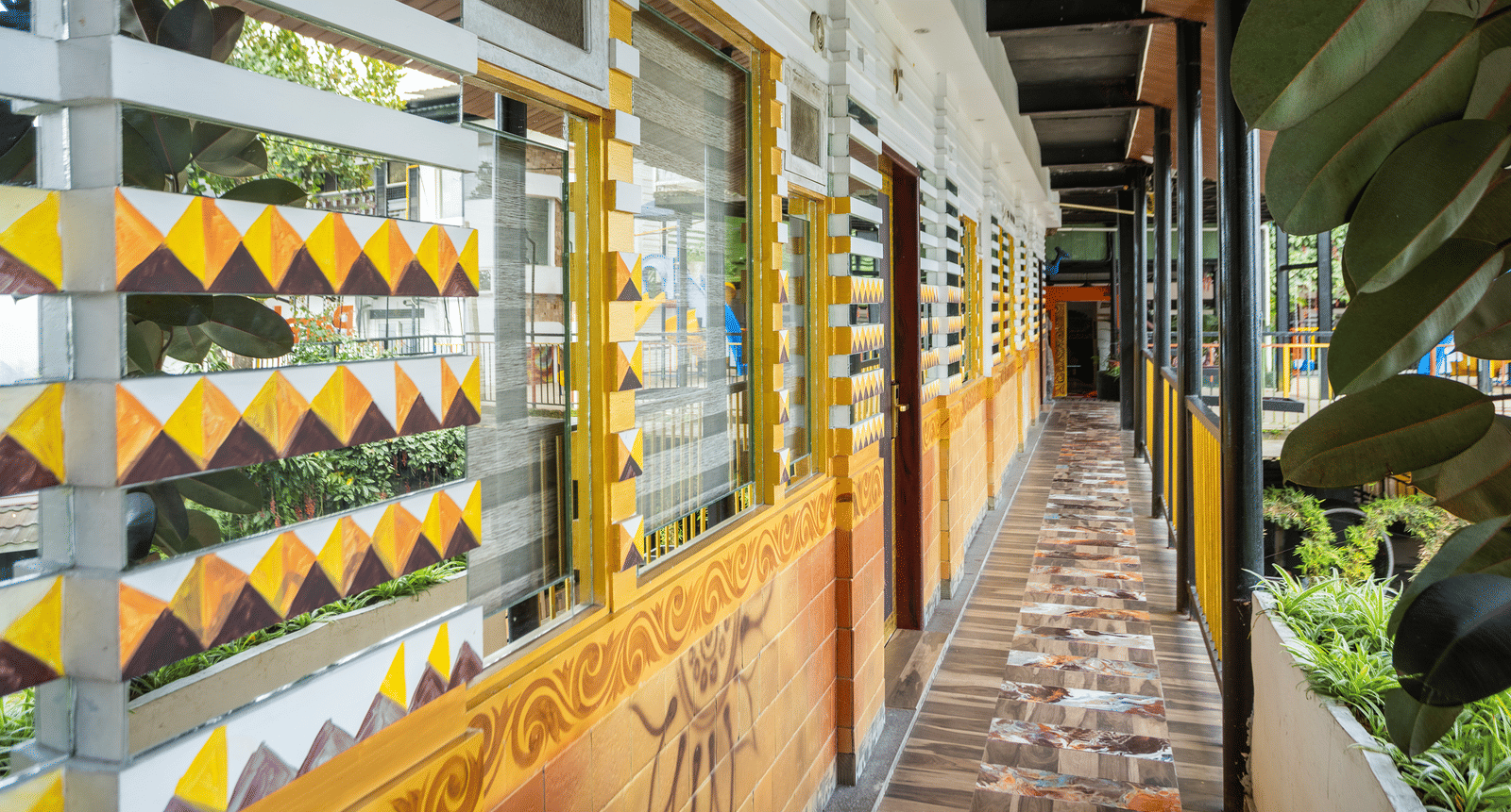 A close-up of the outdoor walkway at Parakkat Nature Hotel and Resorts, Munnar, featuring a wooden railing with a decorative, patterned screen and views of outdoor foliage.