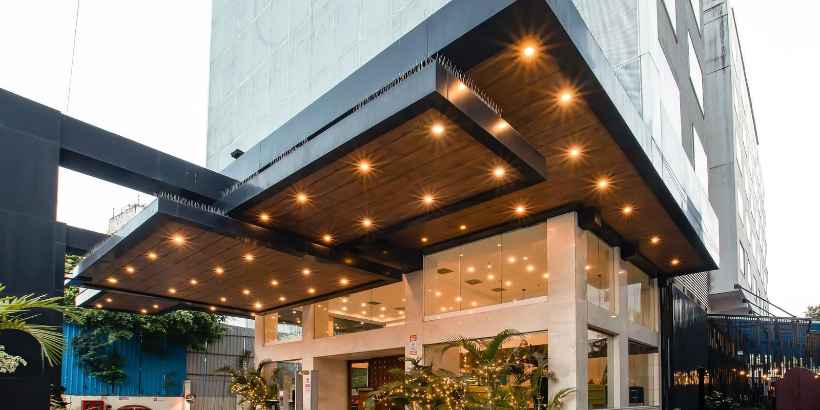 Facade of  The Cunningham Hotel featuring its entrance with a stylish black canopy, warm lighting and glass walls