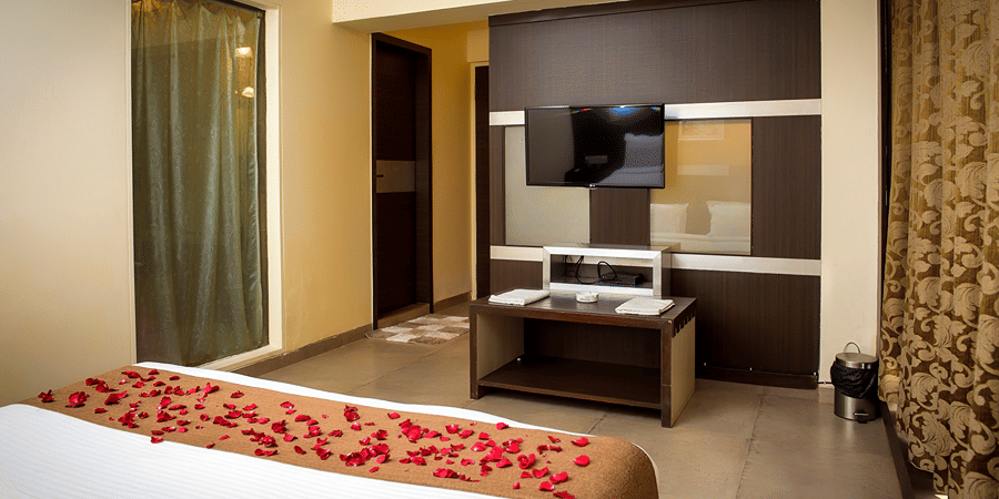 The bedroom of the Royal Suite of the resort with bed, TV, console, AC and floor to ceiling windows.