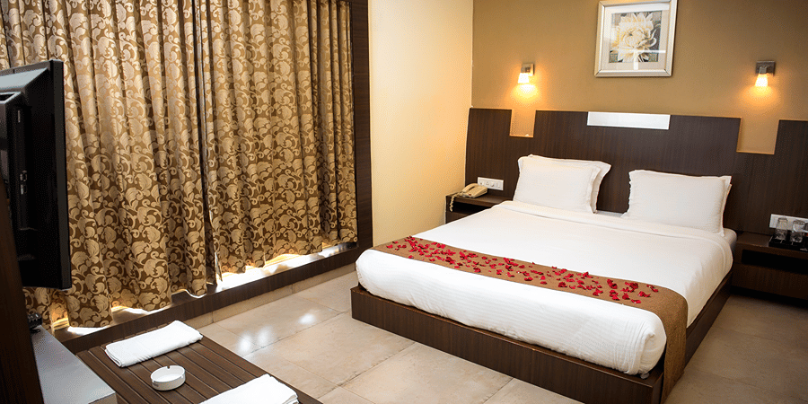The bedroom of the Royal Suite with bed, TV, side tables, wall mounted warm lights, and a console