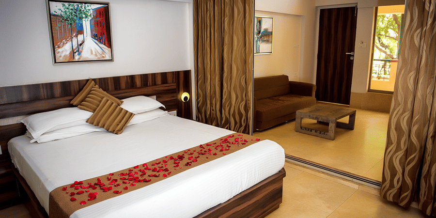 Deluxe villa bedroom interior featuring a bed, sofa and coffee table - Adamo Resort Matheran.