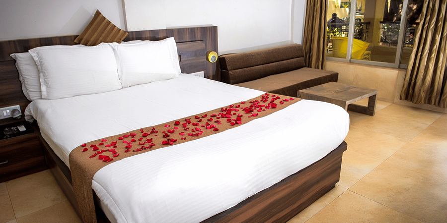 A close up view of the bed in Regent Room with its sofa and glass doors that lead to the balcony.