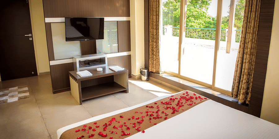 The bedroom of the Royal Suite with bed, TV, console and glass doors leading to the balcony.