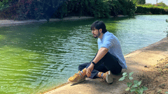 a person sitting by a stream during daytime - Karma Lakelands.