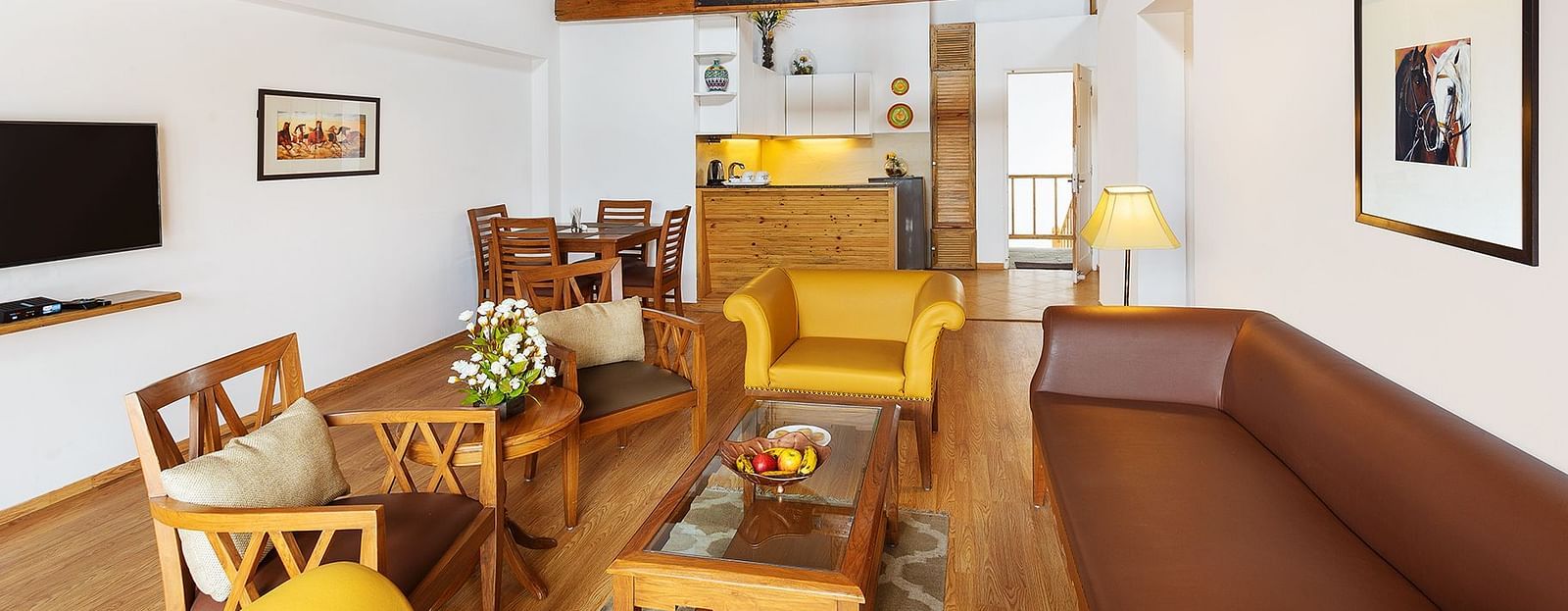 Living room with comfortable sofa and chair with attached kitchenette of Two Bedroom Apartment - The Pinewood Nainital