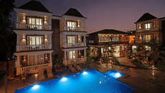 Illuminated building by night with a glowing pool in the foreground - Grand Continent, Anjuna - A Sarovar Portico Affiliate Hotel 