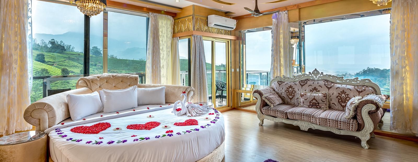 An image of a bedroom with round bed with cushions and next to it is a stylish sofa and the entire room is filled with natural light -  Parakkat hotel & resorts
