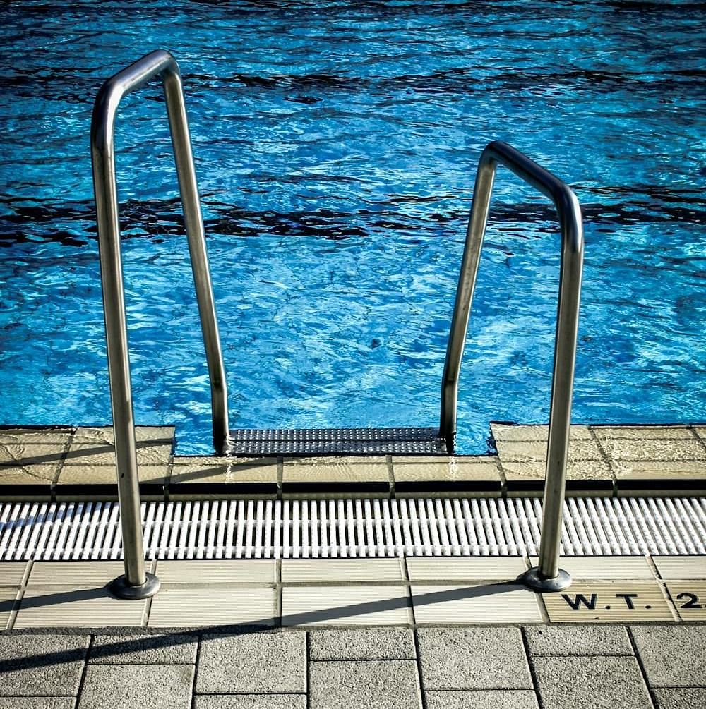 A swimming pool with metal stairs leading to the crystal clear water.