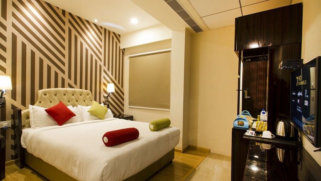 Standard room with bed, television and dressing table at Art Boutique Hotel, Hyderabad