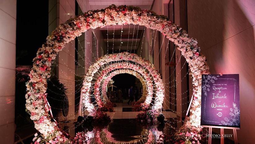 An overview of the entrance with decorated arches and the signage of the groom and bride names - Karma Lakelands.