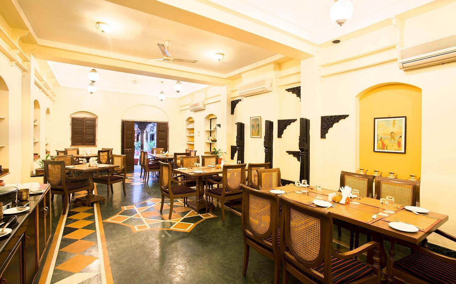 An inviting dining area featuring elegant wooden furnishings, creating a warm and charming atmosphere for guests to enjoy their meals in a scenic setting, The Haveli Hari Ganga, Haridwar: