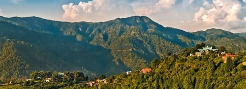 Scenic mountain view of lush green mountains with clouds in the background  captured during the day - Ramgarh Bungalows, Nainital.