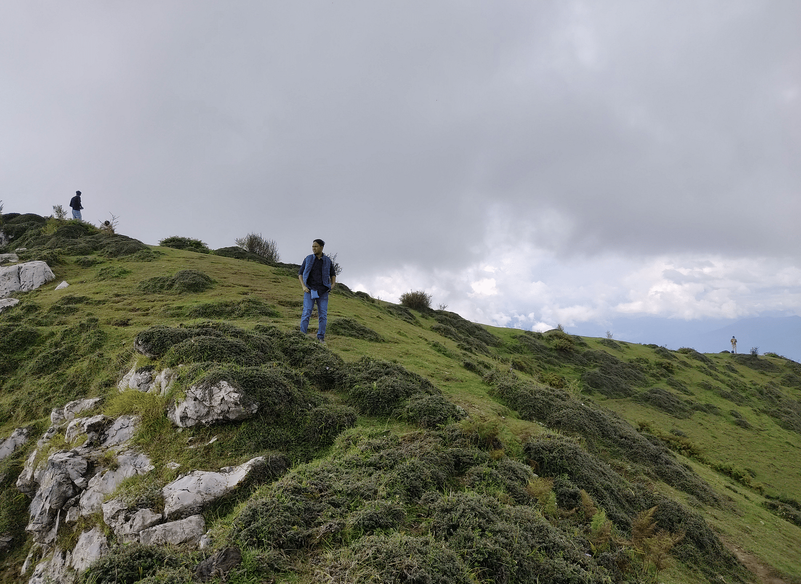 A person standing on a grass-covered mountain.