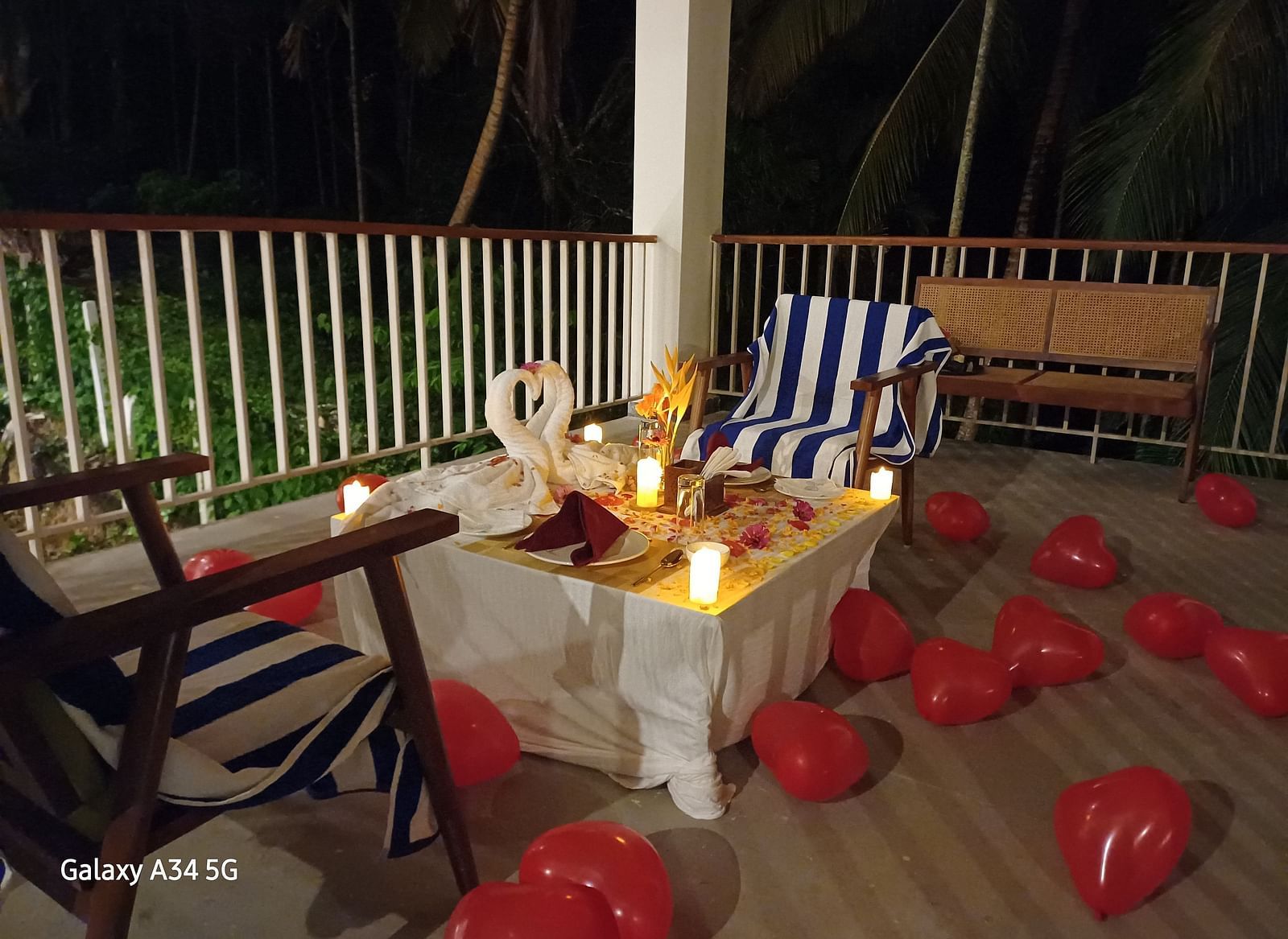 A romantic table setting outdoors at night, with candles, swan decorations, and balloons, creating an intimate ambiance. - Sea Hills Resort, Swaraj Dweep (Havelock)