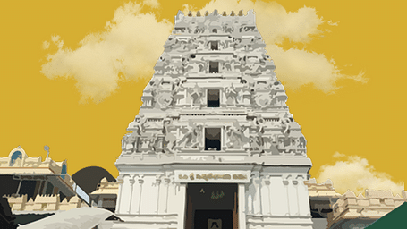 A towering white gopuram of a temple against a yellow background, with a staircase leading up.
