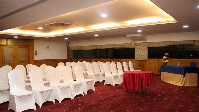 An image showing the chairs facing the dais, with a small round table with red table cloth, beside a small desk and chair - Monarch Hotels