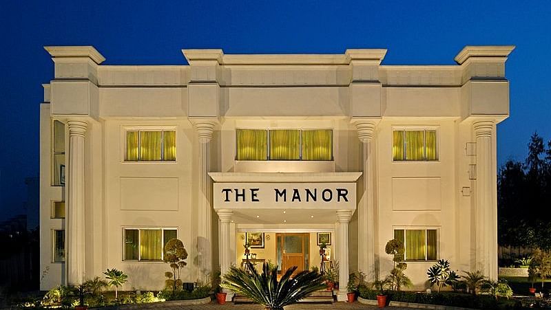 The facade of a hotel featuring small shrubs on either side and a small space at the front for vehicle drop-offs