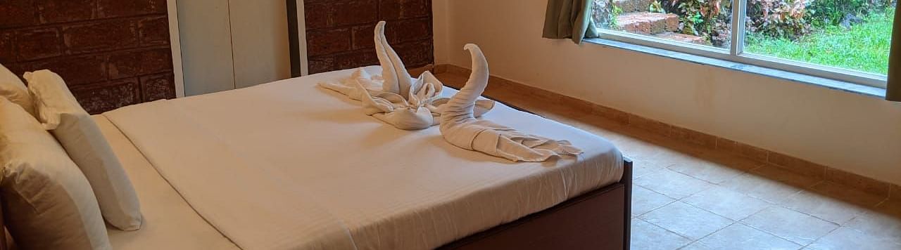 A well-lit bedroom with a large bed, window, and neatly folded towels at The Conservancy Bungalow.