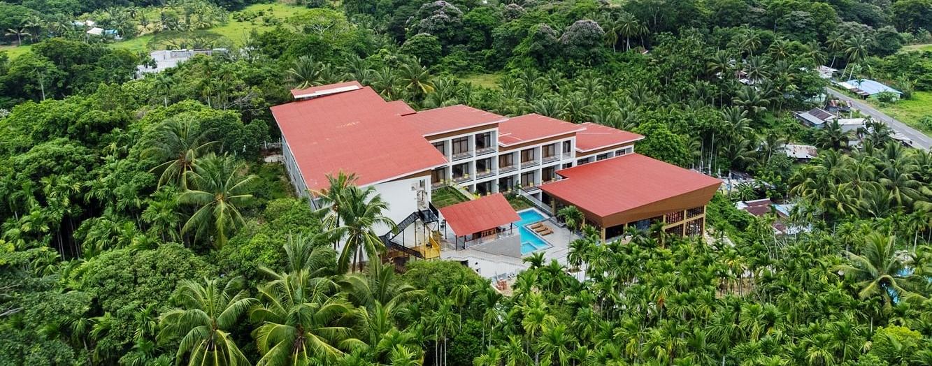 A wide aerial view of a hotel building with red roofs, situated within a dense forest or jungle landscape. - Sea Hills Resort, Swaraj Dweep (Havelock)