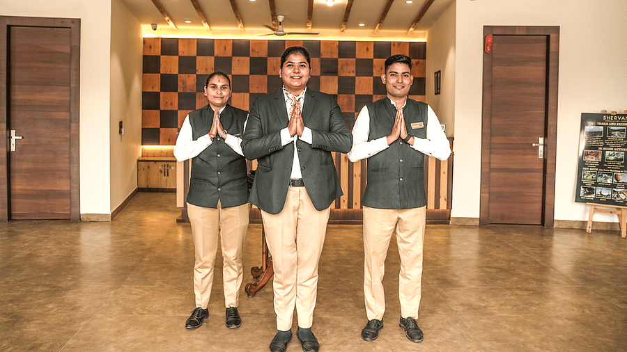 Hotel staff greeting guests with a Namaste gesture in a welcoming lobby - Shervani Pebbles & Pines, Corbett