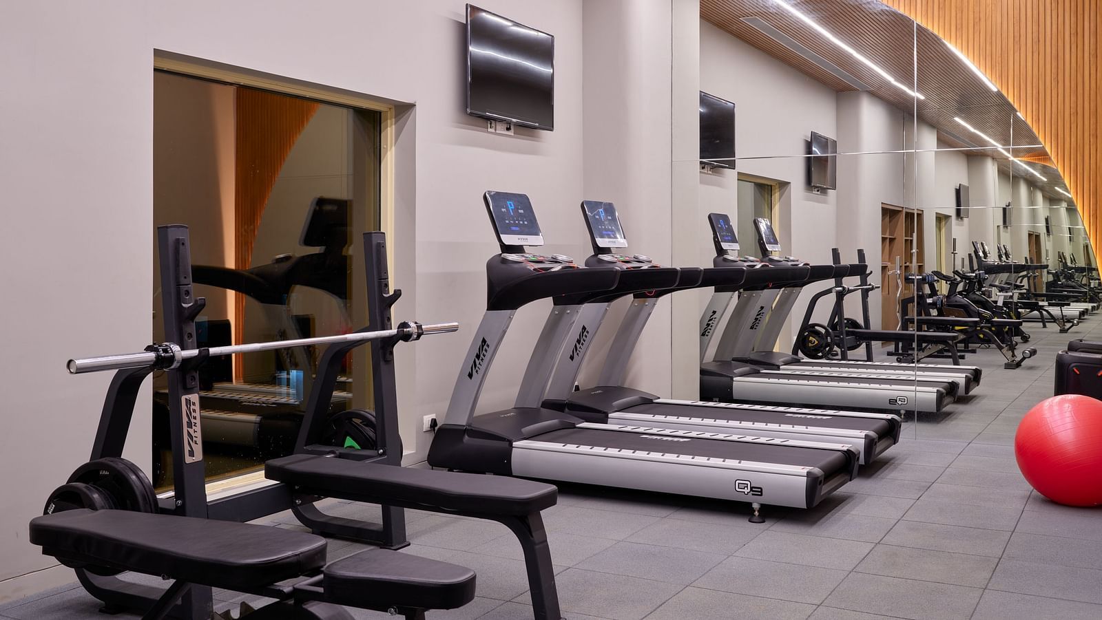 An image of the gym at Swosti Premium Beach Resorts in Puri featuring treadmills along with other equipment under bright lighting