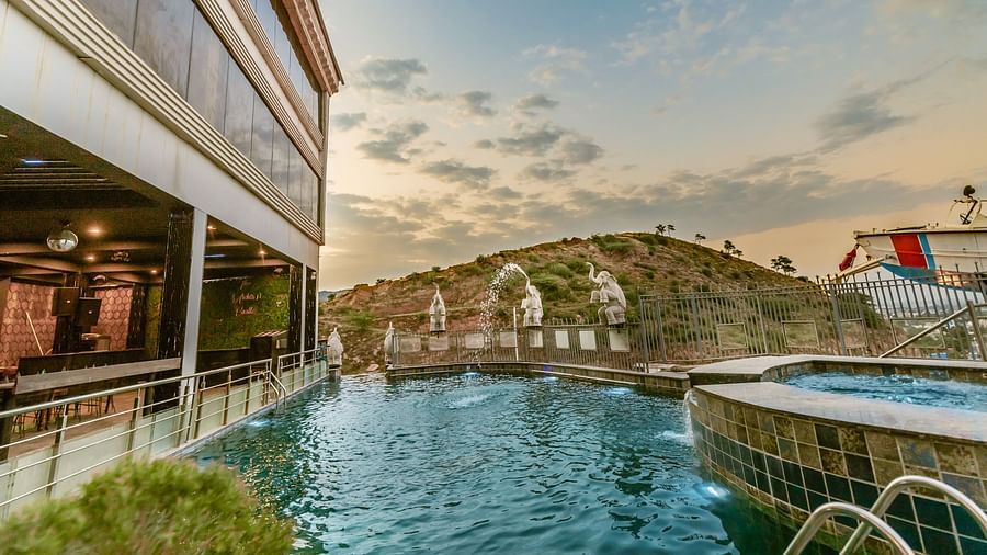 Hotel building with a swimming pool and a view of a hill in the background
