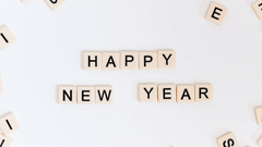 happy new year written from scrabble tiles with other scrabble tiles on the side