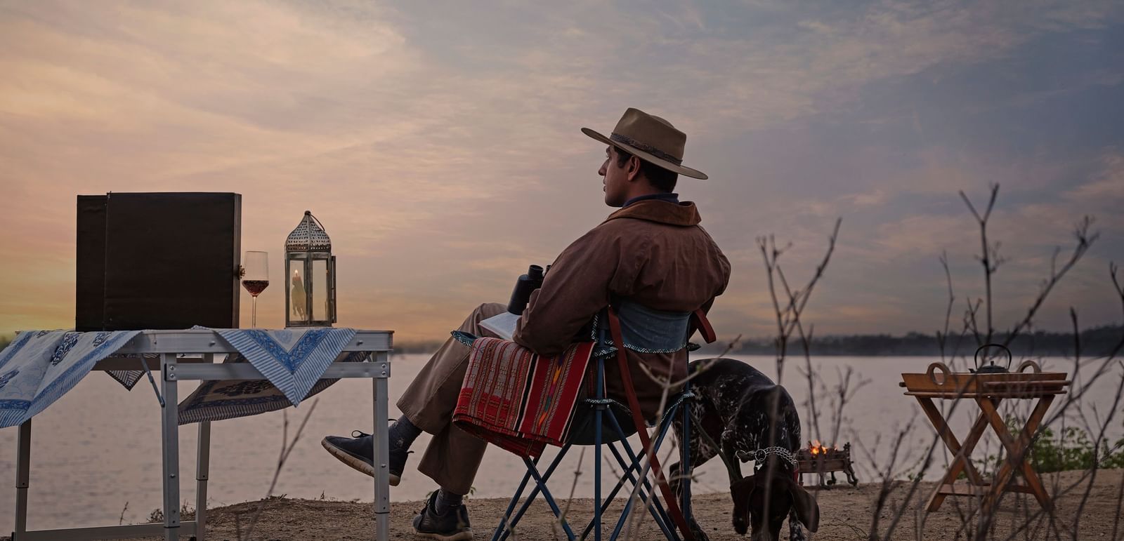 image of a man relaxing and enjoying the mesmerising sunset with a serene lake in front of him at dev shree deogarh