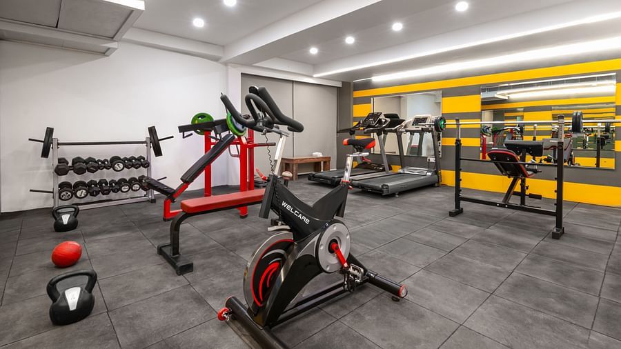A modern gym with various fitness equipment,  and a large mirrored wall in the background - Clarks Inn Express, Near Jammu Bari Brahmana Railway Station